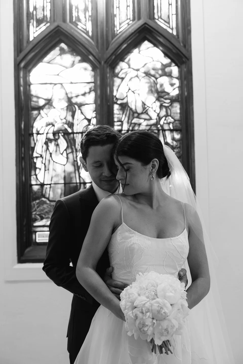Abraço do casal diante de uma janela, em preto e branco.