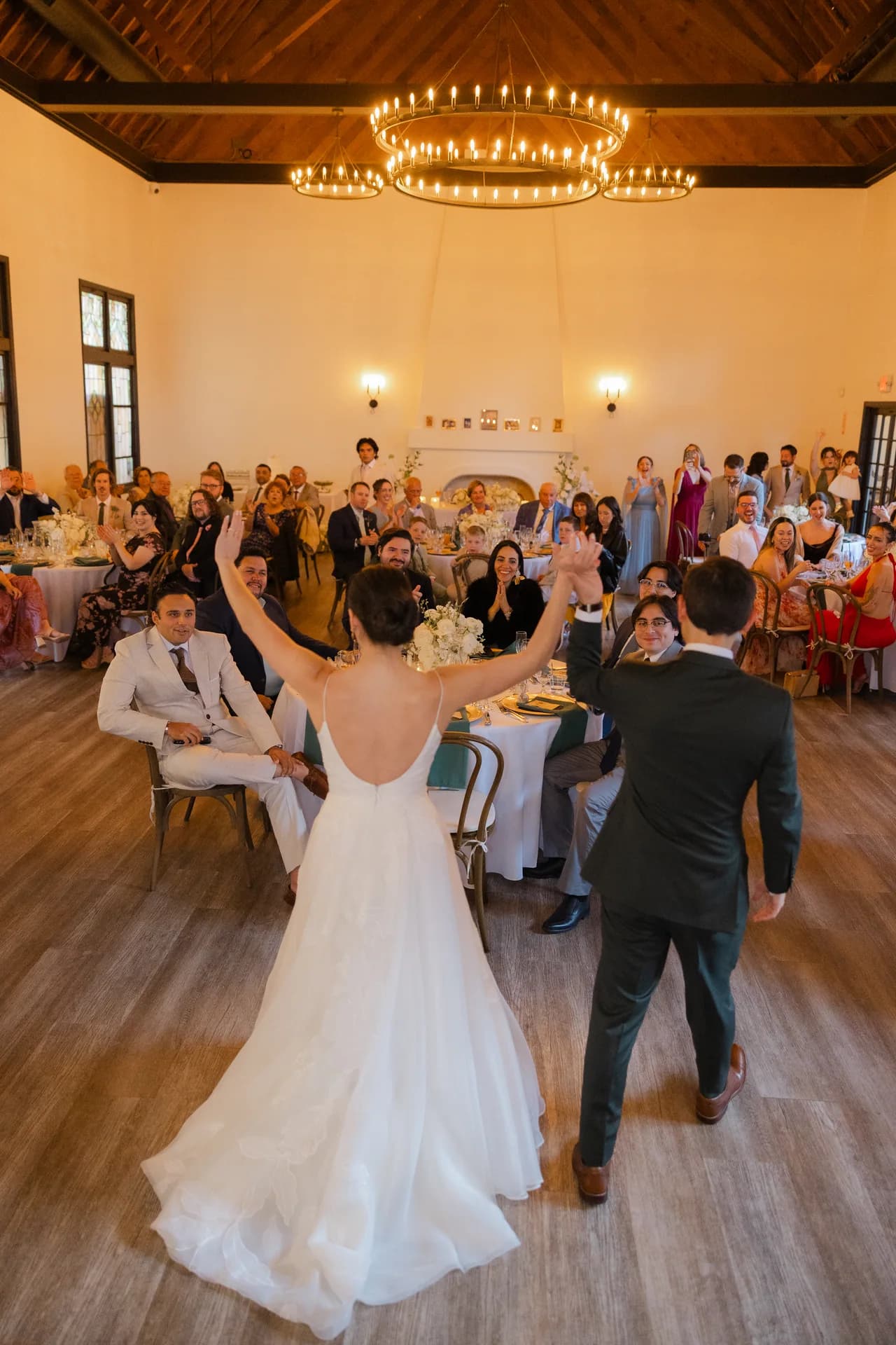 Casal celebrando no salão, cercado pelos convidados.